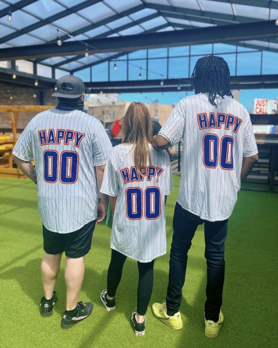 Three people in Happy Camper baseball jerseys, on the Happy Camper Wrigleyville rooftop