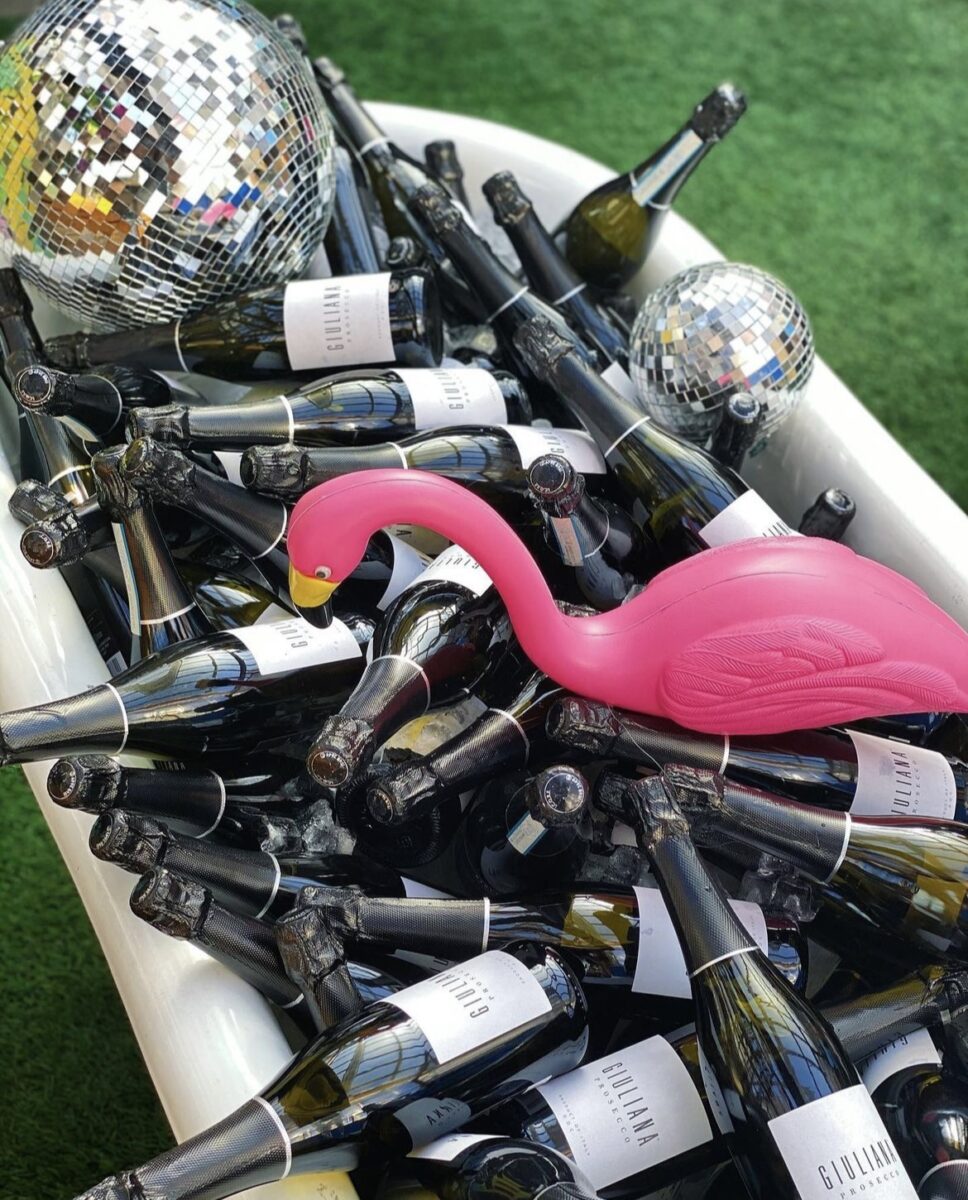 Garden flamingo in a bathtub full of champagne bottles and a disco ball