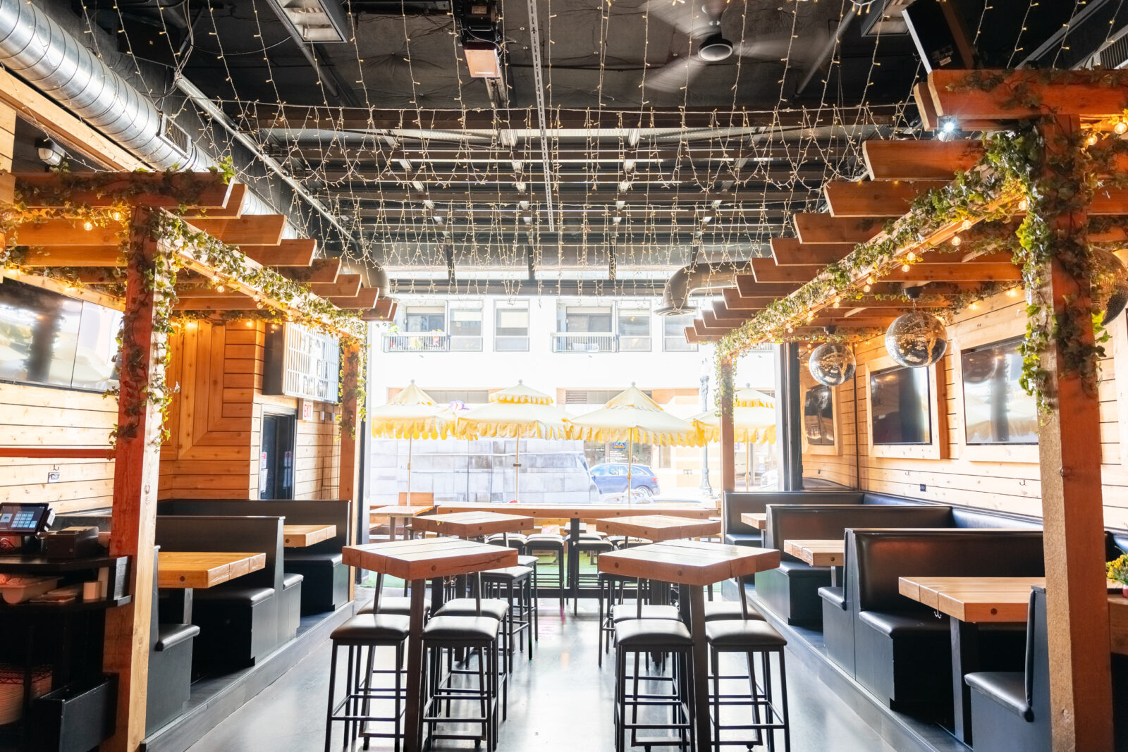 slide 2 of 3 - Indoor seating, with open air garage door, high top tables and booth seating