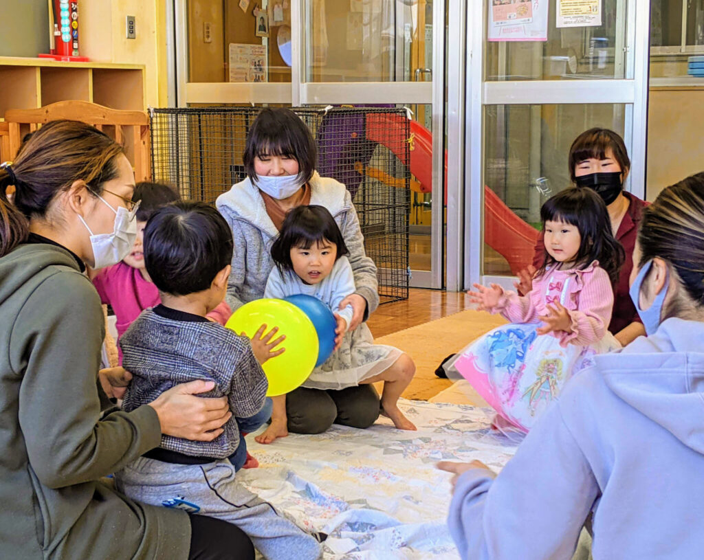 輪になって遊ぶ幼児と親たち