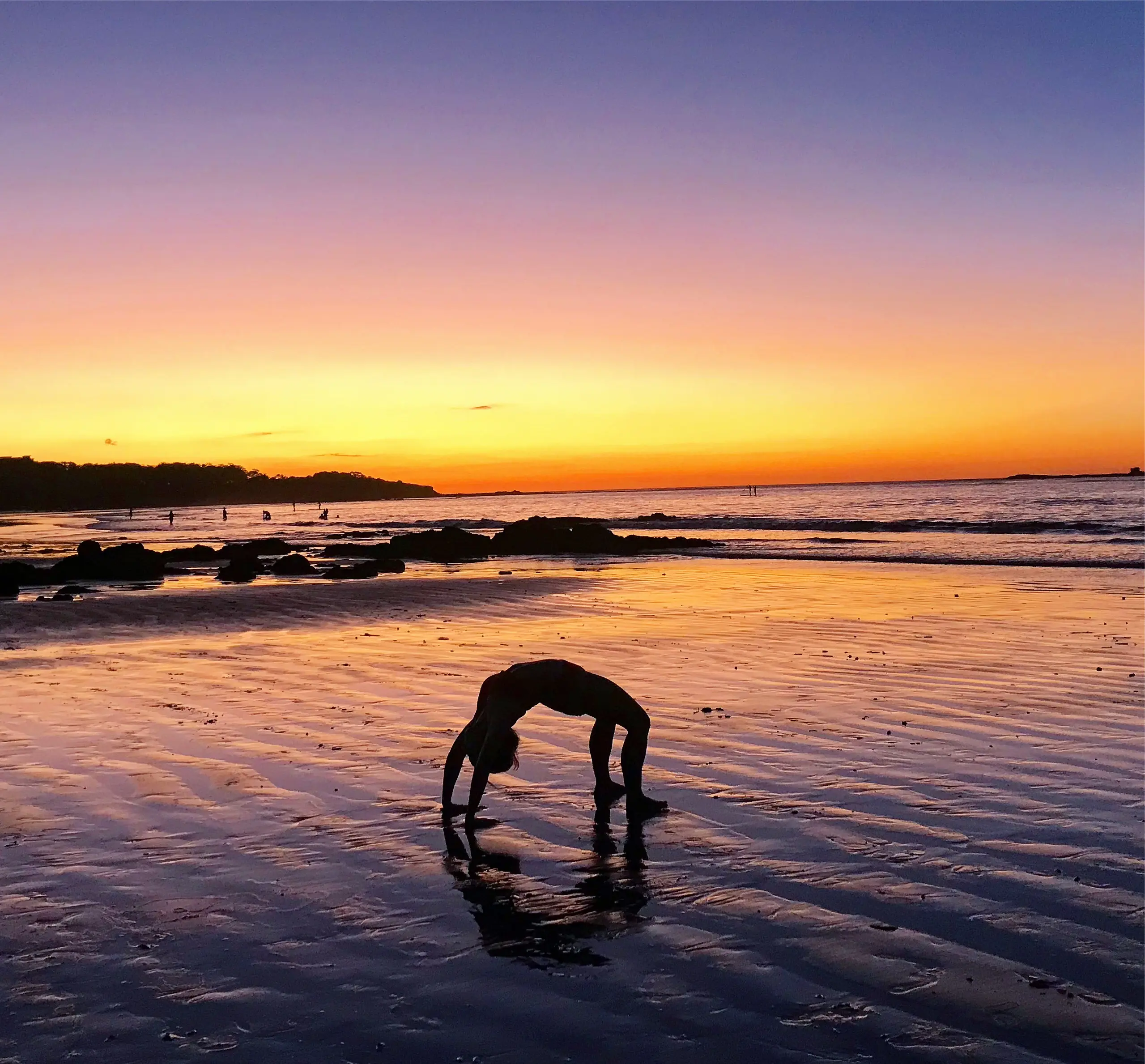 Sunset yoga wheel pose on the beach in Costa Rica