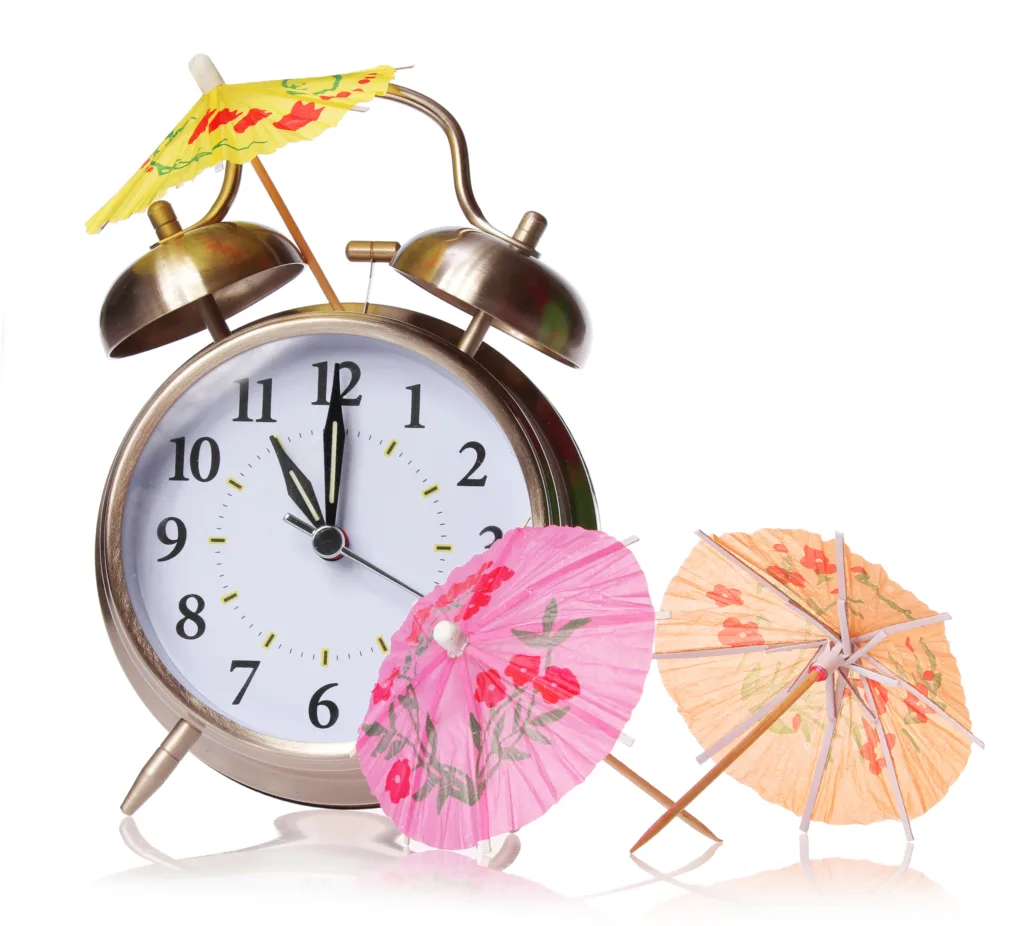 Vintage alarm clock decorated with colorful cocktail umbrellas, symbolizing Hawaiian time and a relaxed island schedule.