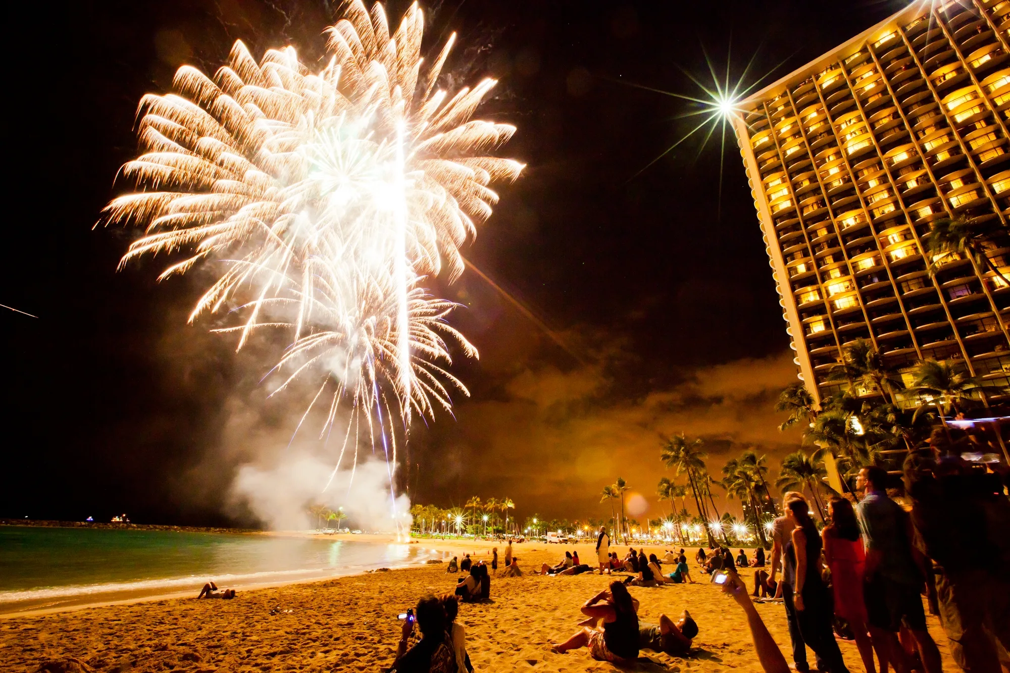 people on a beach watching fireworks