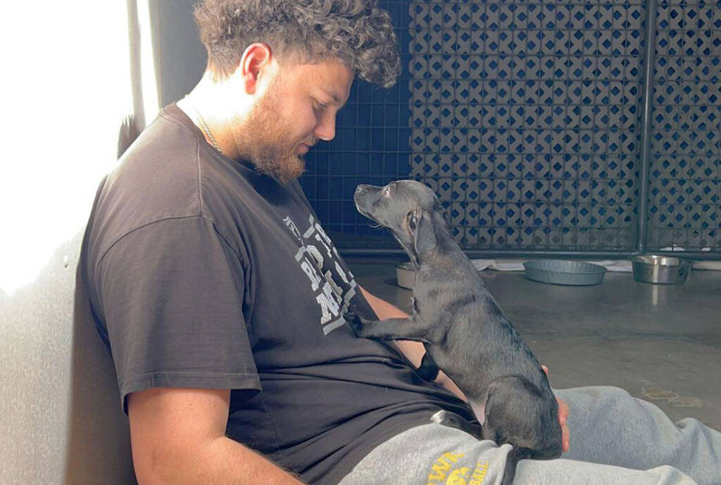 Man sits with black puppy in his lap