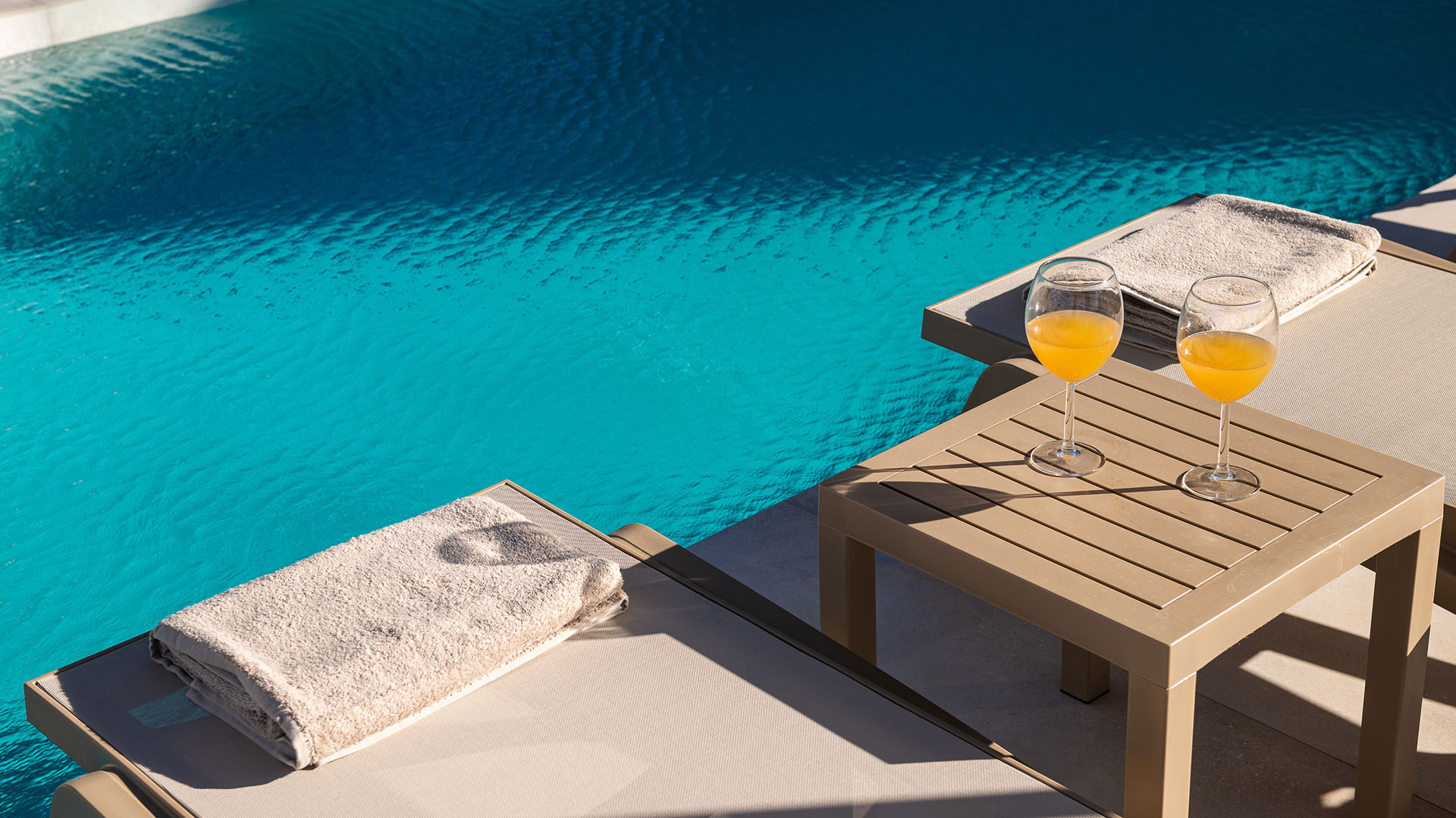 Close photo of a table near the pool and sunbeds