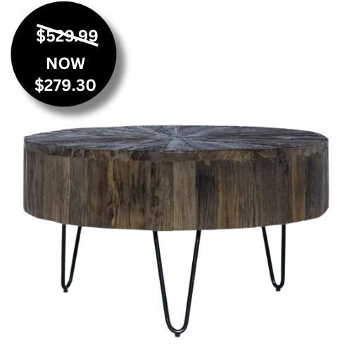 A circular coffee table featuring a thick, drum-style top made of weathered wood with a sunburst-patterned grain on the surface. The top is supported by four black metal hairpin legs. A black sale badge indicates the price has been reduced from $529.99 to $279.30.
