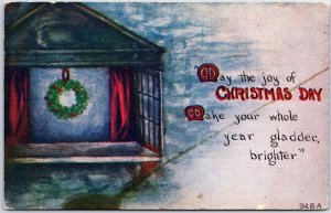 VINTAGE POSTCARD CHRISTMAS WREATH BEHIND A LEDGE IN A CABIN WINDOW c. 1910