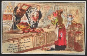 VICTORIAN TRADE CARD JC King Household Goods Clerk Dumps Can on Other Clerk