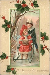 Christmas Little Boy Pushes Girl on Sled Chair Holly Border c1910 Postcard