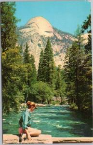Yosemite Woman sitting by Merced River View of North Dome frm Happy Isles Bridge