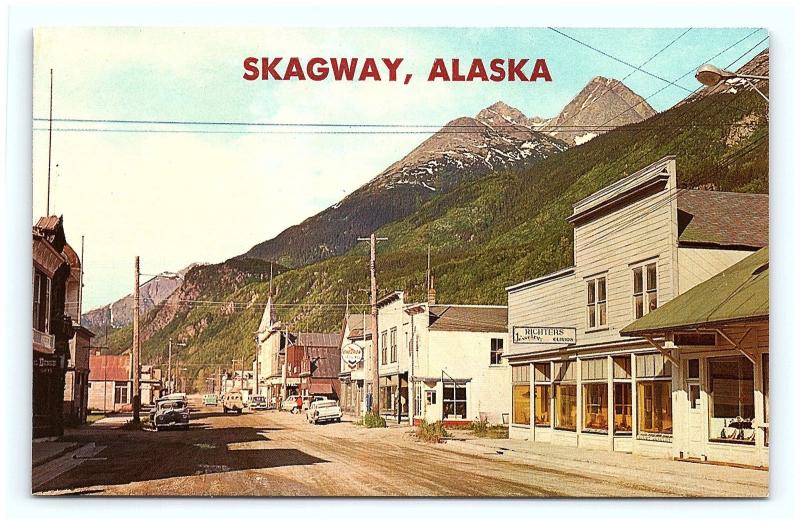 Postcard AK Skagway 1950's Old Cars Street View Chevron Gas Dirt Street G15