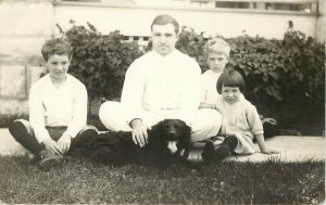 RPPC Postcard Man and 3 Irritated Children Sit With Black Spaniel Dog Unknown US