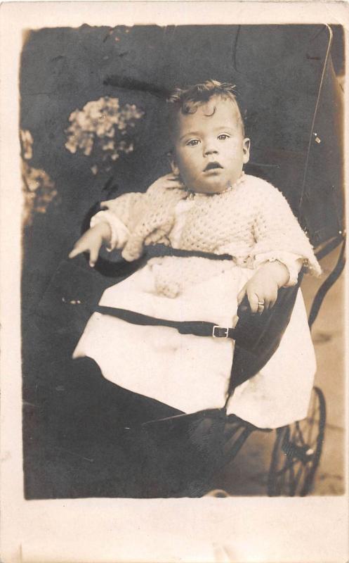 YOUNG CHILD STRAPPED IN CARRIAGE REAL PHOTO POSTCARD c1900s