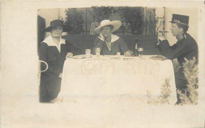 Vintage photo postcard military man cigar smocker at a table with two women