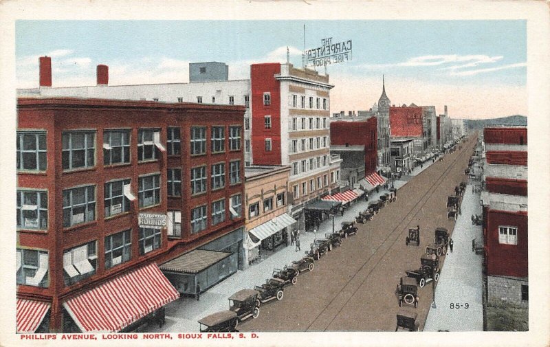SIOUX FALLS SD~PHILLIPS AVENUE LOOKING NORTH-STORE FRONTS-AUTOS~1920s POSTCARD