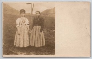 RPPC Two Women Edwardian Dresses Holding Hands In Field Below Mtns Postcard Q23