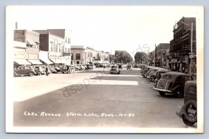 K1/ Storm Lake Iowa RPPC Postcard c1940s Lake Avenue Stores Autos  432