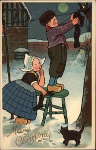 E Nister Christmas Little Dutch Children Hang Stockings Black Cat c1910 Postcard