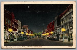 Postcard Delaware OH c1946 Sandusky Street Looking North at Night Old Cars Shops