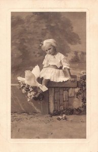 A095 Little Girl on wall 1912 Dove caring letter flowers vintage postcard