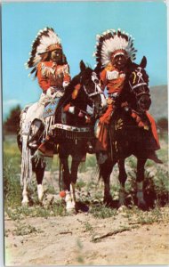 postcard Native Americans in full dress on horseback