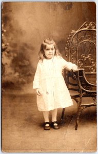 Young Girl in White Patterned Dress, Holding Chair Portrait - Vintage Postcard