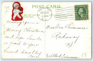 1920 Christmas Greetings Bell Santa Claus Sleigh Holly Berries Embossed Postcard