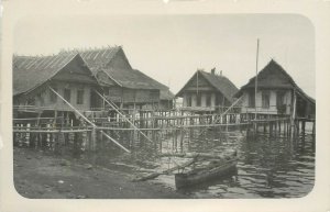 c1909 RPPC New Caledonia Man Repairs Roof Houses on Stilts over Water, Outrigger