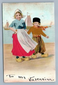 VALENTINE ANTIQUE EMBOSSED POSTCARD DUTCH KIDS IN APPLIQUE CLOTH DRESSES