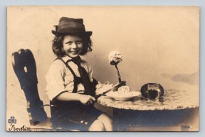 Smiling Child in Hat Sits at Table Vintage Postcard 1172