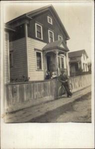 Fence in Front of Man - Man Leans on Old Bicycle c1910 Real Photo Postcard