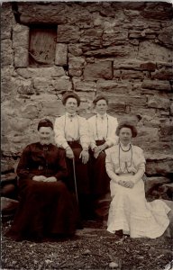 VINTAGE POSTCARD GROUP OF 4 WOMEN SEATED IN FRONT OF STONE STRUCTURE c. 1910s