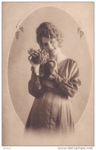 Woman holding cluster of grapes wearing a long satin dress, 00-10s