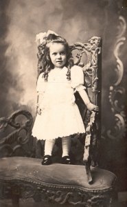 Portrait Of Cute Baby Girl Standing By Chair Hudson Vintage Postcard Real Photo