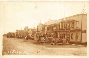 La Sarre Quebec Dirt Street Storefront Old Cars Truck in 1938 Real Photo PC 
