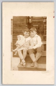 RPPC Cute Kids Hugging Girl With Antique Doll On Porch Steps 1930s Postcard S30