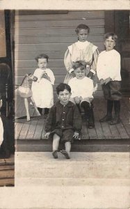 RPPC CHILDREN ON PORCH ROCKING HORSE REAL PHOTO POSTCARD (c.1910)