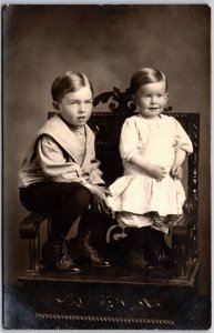 Sibling Photograph Sitting On A Wooden Chair Real Photo RPPC Posted Postcard