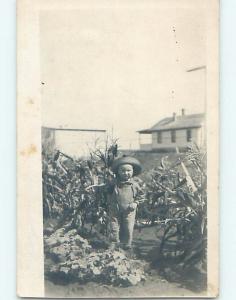 Pre-1920's rppc BOY IN OVERALLS AND STRAW HAT BESIDE CORN HM0673