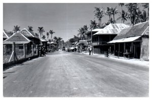 Stores on palm tree lined street in Guiuan Samar Philippines 1945 RPPC Postcard