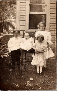 RPPC Two girls boy and baby in chair outside house Kruxo 1908-20s