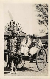 New Guinea? Male traditional dress pulling tourist cart Rppc