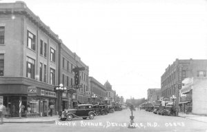 Devils Lake ND Fourth Ave. Very Clear Storefronts Old Cars Signage RPPC