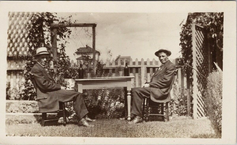 Two Men Sitting Table With Bottles Alcohol ? Outdoors Unused RPPC Postcard G15