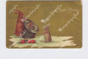 PPC POSTCARD EASTER BUNNY RABBITS PLAY WITH TOP HAT EGGS ON GROUND HOLDING FLOWE