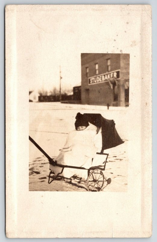 Real Photo Postcard~Baby in Wheel Barrow Pull Cart~Studebaker Building~1910 RPPC 