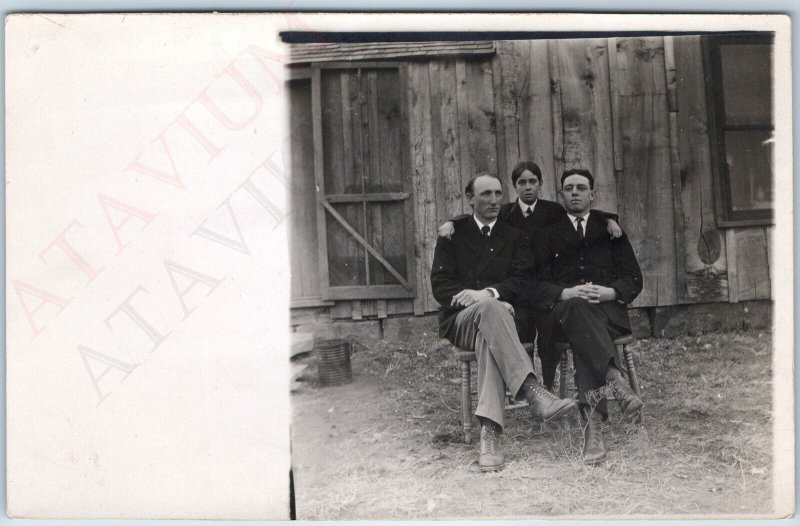 c1910s Handsome Group Men RPPC Pose Farm Chair Rustic Barn Plank Wall House A213