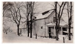 Woman standing in the snow outside of an old home RPPC Postcard