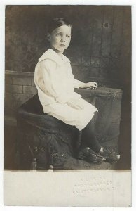 RPPC,  A Young Boy Sitting on a Seat Near a Stone Wall