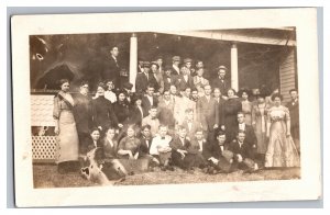 Postcard Large Group Of Men And Women Posing In Front Of Old House RPPC 